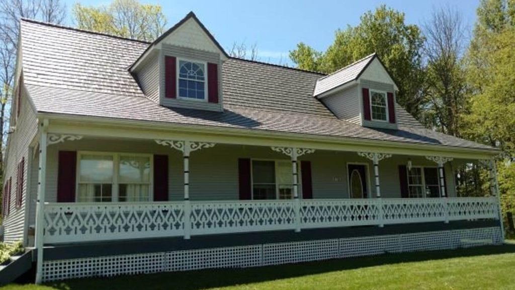 Classic well-maintained American country home with asphalt shingle roof and grassy yard.