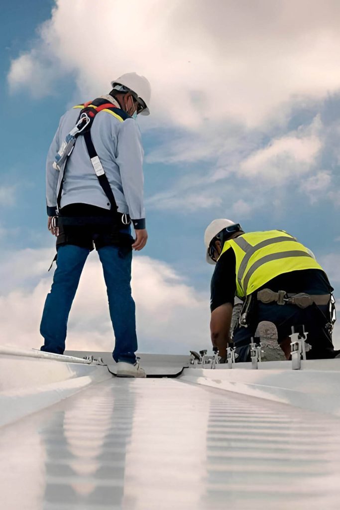 Two workers on the roof assessing the need to replace the roof of a commercial property.