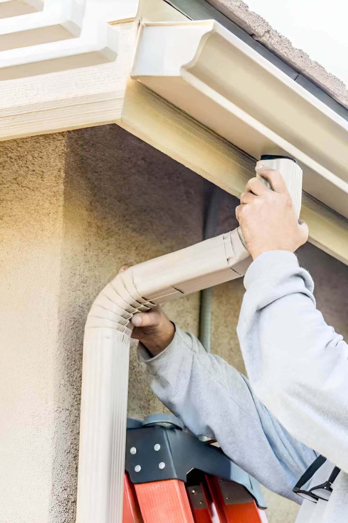 Detail of worker changing the discharge pipe and connecting it to the renovated gutter.