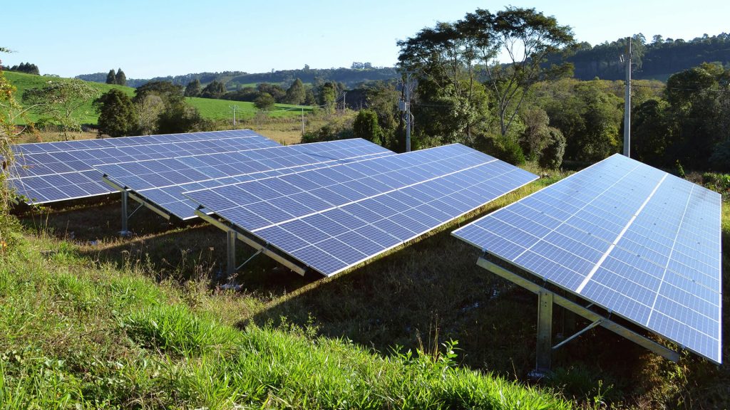 Several solar panels installed at ground level amidst fields and pastures.