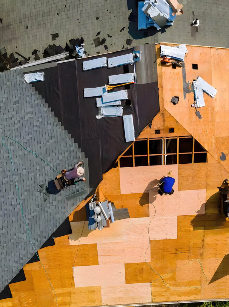 Aerial view of a group of workers replacing and repairing a residential asphalt shingle roof.
