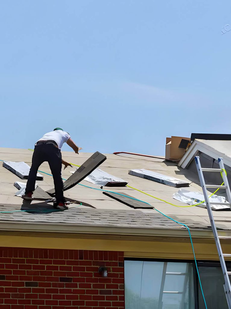 Worker doing maintenance on residential roof by installing new asphalt shingles.