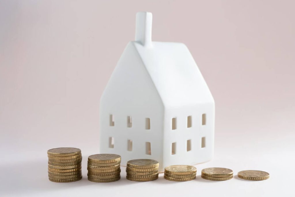Miniature house with some coins demonstrating savings with the new roof.